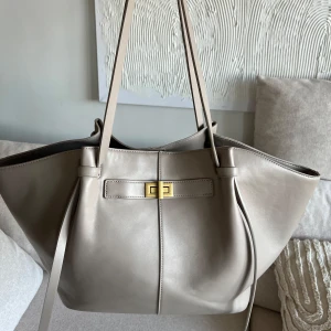 Long strap pu bag GINA TRICOT - Snygg beige axelväska i läderimitation med stilrena gulddetaljer. Väskan är väldigt rymlig som ni ser på bild.  Den är i mycket fint skick, orginalpris: 500kr