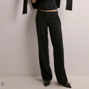 Svarta kostymbyxor - Säljer ett par svarta kostymbyxor i nyskick. De är högmidjade och har en straight passform. Perfekta för både vardag och fest! Byxorna är gjorda av ett bekvämt och slitstarkt material som känns skönt mot huden. De har en dragkedja och knappar framtill för enkel på- och avtagning.