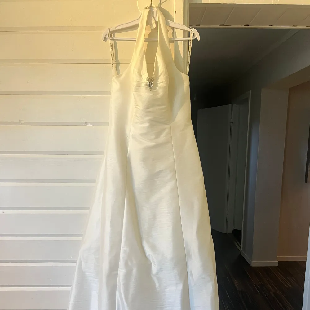 Bröllopsklänning halterneck i storlek 42 i färg ivory (creme vit), använd en gång 2010. Hängt i klädfodral som följer med, inköpt på klädpiraten i Gävle för 6500kr. Klänningar.