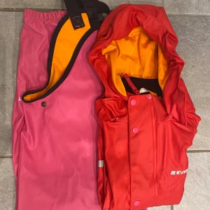 Regnställ  - Jacka och Hängselbyxor, rosa/röd/orange.