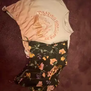 Säljer två snygga croppade toppar från H&M. Den ena är beige med tryck i orange och texten 'Creating Goals For Me'. Den andra är mörkgrön med ett blommigt mönster i rosa, lila och gult samt texten 'Endless Dreams'. Båda topparna har korta ärmar och en elastisk nederkant för en bekväm passform.