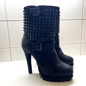 ASH Boots med grov Stilettklack & Sula - Kan användas på vintern när det snö då dom inte alls är hala!Reglerbara remmar på sidan. Dra på modell Storlek: 37, Klackhöjd: 12cm, Plattå höjd: 4cm Material: Mocka och nitar. Nypris: ca 3000 SEK. Skick: Använda med spår av användning men fina.