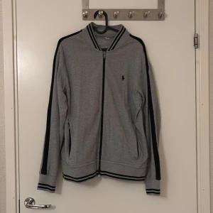 Skitsnygg polo Ralph lauren zip up - Jag säljer min unisex polo Ralph lauren zip up som passar i många olika årstider och som saknar tecken på användning. Har två stängbara fickor på sidorna.
