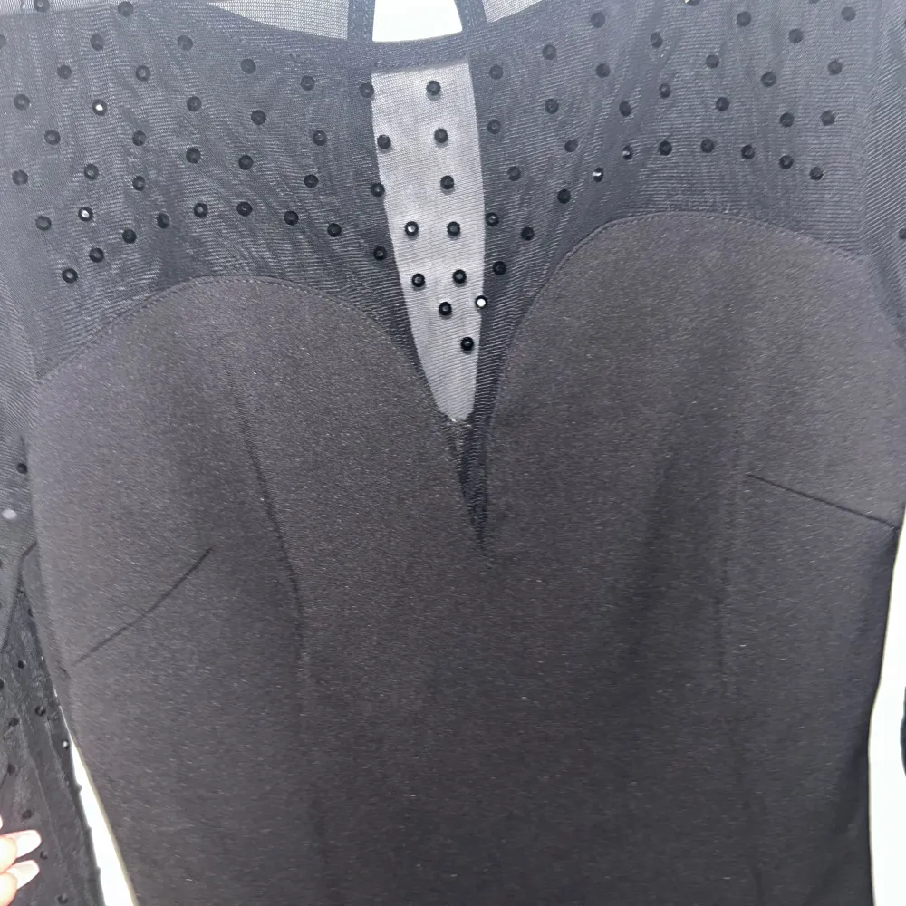 Säljer en elegant svart klänning från Betsey Johnson. Den har långa ärmar med prickigt mönster i mesh och en snygg v-ringad detalj framtill. Perfekt för festliga tillfällen! ✨I nyskick och sitter jätte fint.. Mekot.
