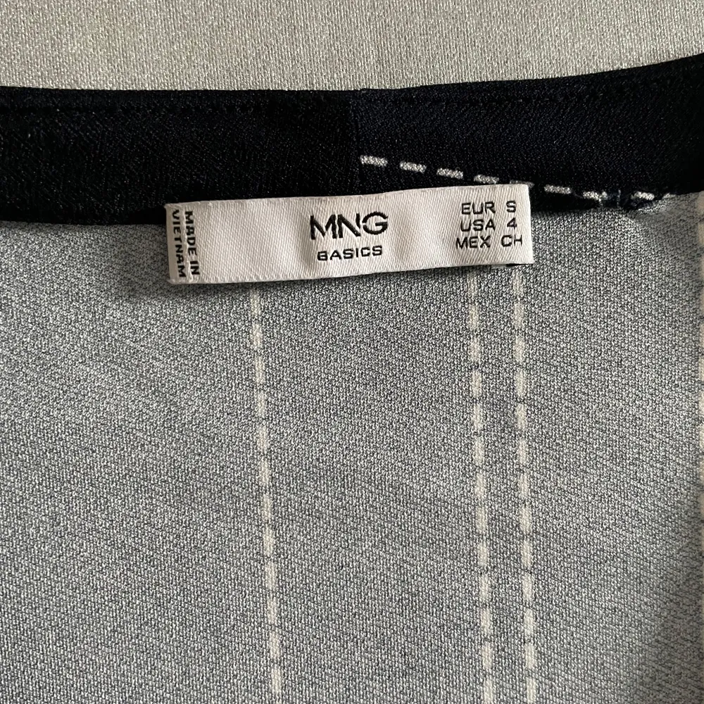 Säljer en elegant marinblå klänning från MNG Basics med vita ränder i ett snyggt mönster. Klänningen har trekvartsärm och en v-ringad hals. Perfekt för både vardag och festliga tillfällen. Den är i nyskick och passar bra till höst och vår.. Klänningar.