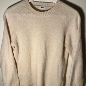 Beige stickad tröja från Uniqlo - Säljer en stilren beige stickad tröja från Uniqlo. Tröjan har en rund halsringning och långa ärmar, perfekt för kyligare dagar. Den är mjuk och bekväm, idealisk för både vardag och avslappnade tillfällen.