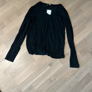 Svart långärmad tröja - Säljer en stilren svart långärmad tröja med v-ringning. Perfekt för lager-på-lager eller som den är. Enkelt och tidlöst plagg för garderoben. Ny med prislapp kvar. Inköpspris: 199kr. 