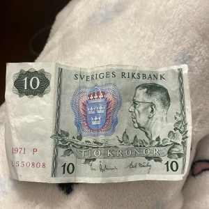 Svensk tiokronorssedel från 1971 - En svensk tiokronorssedel från 1971 med porträtt av Gustav VI Adolf. Sedeln har en grön och blå design med snöflingemönster på baksidan. Serienummer L550808.