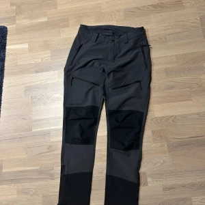 Grå och svarta byxor med dragkedjor - Snygga grå byxor med svarta detaljer och praktiska dragkedjor på benen. Perfekta för en aktiv livsstil med en modern look.