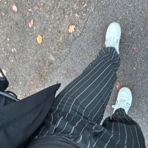 Svarta randiga byxor - h&m - Snygga svarta byxor med vita ränder. Perfekta för en stilren look. Byxorna har en loose passform och är bekväma att bära.