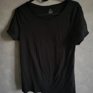Svart t-shirt från Our Best Basics - En klassisk svart t-shirt från Our Best Basics, tillverkad i ekologisk bomull. Perfekt för en enkel och stilren look. T-shirten har en normal passform och korta ärmar.