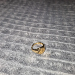 Stol guld ring - Elegant guldfärgad ring med en rund, slät yta på toppen. Perfekt för att ge en stilren touch till din outfit.