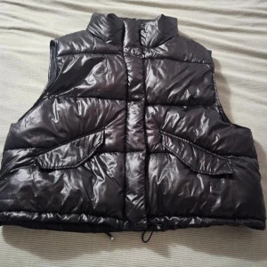 Svart dunväst - Snygg svart dunväst från H&M med dragkedja och praktiska fickor. Perfekt att matcha med olika outfits. Storlek xs
