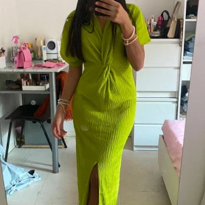 Limegrön klänning med slits - Trendig limegrön klänning med en smickrande knutdetalj framtill och en elegant slits. Klänningen har korta ärmar och en åtsittande passform som framhäver figuren. 