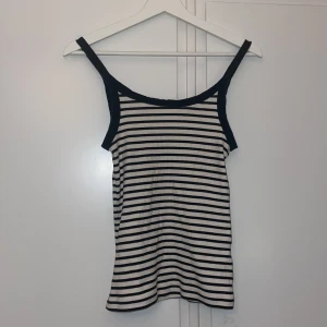 Randig linnetopp från H&M - Snygg randig linnetopp från H&M i svart och vitt. Toppen har smala axelband och en ribbad struktur som ger en skön passform. 