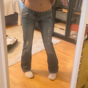 Blå bootcut jeans från Great Jeans - Snygga blå bootcut jeans från Great Jeans med slitna detaljer. Perfekta för en avslappnad stil. De har en knapp och dragkedja framtill.