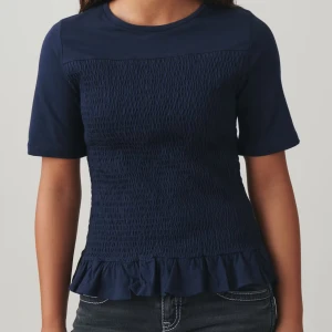 Mörkblå topp med volangdetalj - Snygg mörkblå topp med korta ärmar och volangdetalj vid nederkanten. Toppen har en smockad textur som ger en fin passform. Perfekt för en stilren look.