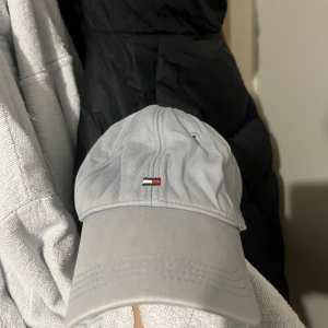 Ljusblå keps från Tommy Hilfiger - Snygg grå keps från Tommy Hilfiger med det klassiska logotypmärket framtill. Perfekt för en stilren och avslappnad look. Justerbar passform för optimal komfort.