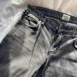 Grå jeansbyxor från C&A - Snygga grå lågmidjade jeansbyxor från C&A med en klassisk femficksdesign. Byxorna har en dragkedja och knapp framtill. Perfekta för en avslappnad stil. 