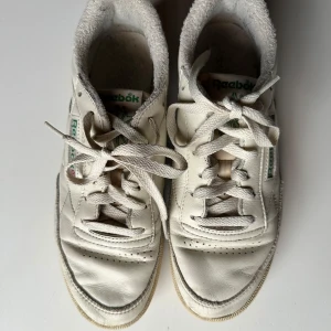 Reebok Club C 85 vintage  - Säljer dessa skor som var populära för några år sen. Krämvita och med grön logga, snygga nu till hösten.   Använda några gånger men i mycket gott skick! Har stått i garderob utan att användas nu i något år.