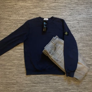 Mörkblå tröja från Stone Island Junior - Snygg mörkblå tröja från Stone Island Junior med det ikoniska märket på ärmen. Perfekt för en stilren och avslappnad look. Sitter riktigt skönt, använder den sällan så säljer den därför! Tröjan sitter som storleken small!