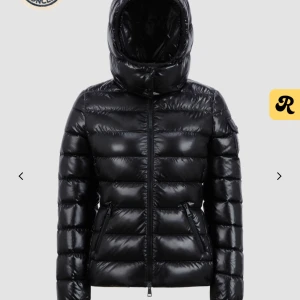 Svart Bady Moncler - Svart pufferjacka från Moncler med huva och dragkedja. Perfekt för kyliga dagar med sin vadderade design. Jackan har en figurnära passform och är ett stilrent val för vintern. Köpt på moncler butiken i London för två år sen, varsamt använd under första vintern med den 😇Pris kan diskuteras vid snabb affär 🥰