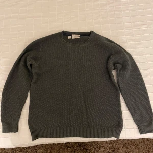 Grå stickad tröja från PL & CO - Säljer en stilren grå stickad tröja från PL & CO. Tröjan har en klassisk rund hals och långa ärmar med ribbade muddar. Perfekt för kyligare dagar. Storlek S och den är knappast använd. Riktigt härlig färg och kvalitet.