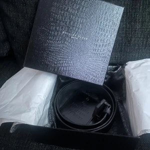 Svart bälte från Philipp Plein - Snyggt svart bälte från Philipp Plein med en unik spänne-design. Kommer i en elegant förpackning med märkets logotyp. Bältet är i nyskick och endast testats. 