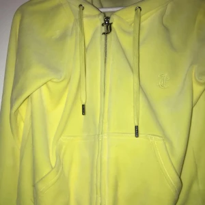 Gul hoodie från Juicy Couture - Säljer en gul hoodie från Juicy Couture med dragkedja och huva. Den har en broderad logga på bröstet och praktiska fickor framtill. Perfekt för en avslappnad stil.har en liten fläck vid dragkedjan men den går bort i tvätten.den har används 1 gång.storlek M men funkar som S också 