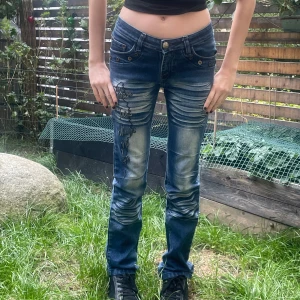 Blå jeans med slitningar - Säljer ett par snygga blå jeans med coola slitningar på framsidan. De har en låg midja och en utsvävnd passform.❤️