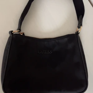 Svart axelväska från Guess - Säljer en stilren svart axelväska från Guess. den är i nysick  . nypris är runt 1200 och kom privat för mer bilder