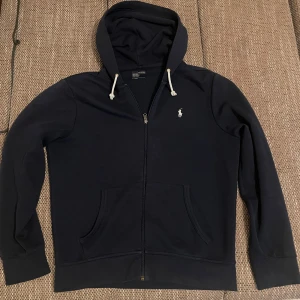 Ralph Lauren Zip-Up-Hoodie - Hej, säljer denna otroliga fina  marinblåa tröja då jag ej använder den längre! Den är i M och är i otroligt bra skick!   Fraktmetod som liten så frakten blir så billigast som möjligt! Den ser svart ut men är i väldigt fint marinblå!