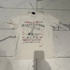 Vit t-shirt från Ralph Lauren - Säljer denna vita t-shirt från Ralph Lauren med tryck i rött och svart på framsidan. Skicket på t-shirten är 8/10 och storleken 10-12 år! Orginal pris - 600kr Vårat pris - 119kr! Priset är inte hugget i sten! Skriv vid minsta lilla fundering!🙌