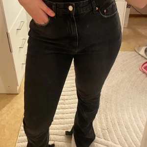 Svarta jeansbyxor - Snygga svarta jeansbyxor med hög midja och med slit nere vid benen. Från gina tricot