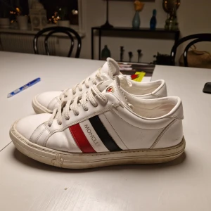 Vita Moncler Dojor - Tja säljer dessa moncler dojor men är även INTRESSERAD AV BYTEN. Priset går också att förhandla. De är 41 men passar bra på mig som har 42. De är stilrena och är lätta att matcha. De är i bra skick och har inge defekter bara smuts.