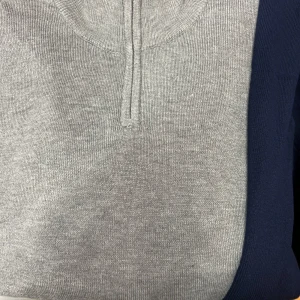 Grå och marinblå tröja med dragkedja - Snygg grå tröja med marinblå ärmar och en praktisk dragkedja vid halsen. Perfekt för en stilren och avslappnad look.