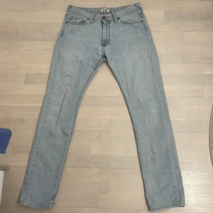 Ljusblå jeans från Acne - Snygga ljusblå jeans från Acne med klassisk femficksdesign och knappgylf. Perfekta för en avslappnad stil. Märkesdetaljer på knappen och bakfickan ger en exklusiv touch. Hör av dig vid minsta fundering 