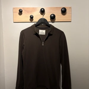 Mörkgrön pikétröja från Jack & Jones - Snygg mörkgrön pikétröja från Jack & Jones med dragkedja framtill. Perfekt för en stilren look. Tröjan har långa ärmar och en klassisk krage. Kolla profil för bundle