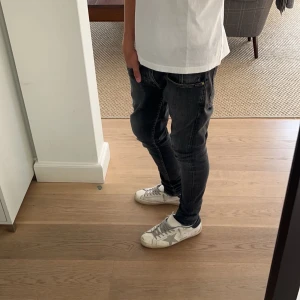 Svarta jeans med slitningar - Snygga svarta jeans med en cool slitningseffekt. De har en klassisk bekväm passform. Perfekta för en avslappnad stil. Svingoa med bra skick!