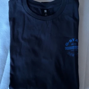 t-shirt från G-Star RAW - Snygg mörk blå t-shirt från G-Star RAW med blått tryck på bröstet. Perfekt för en avslappnad stil. Tillverkad i mjukt material för extra komfort.