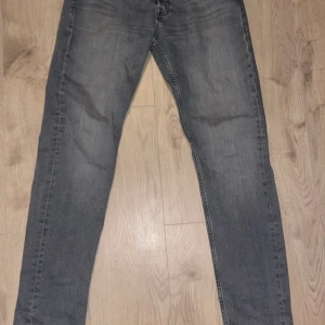 Grå jeans från Jack & Jones - Snygga grå jeans från Jack & Jones med en tapered passform. Perfekta för en avslappnad stil. De har en klassisk design med fem fickor och dragkedja. Modell Tapered/Mike. Storlek W31 L34. För bättre bilder skriv gärna! Det blev nått fel när jag skulle ladda upp bilderna så det är därför man inte ser hela bilden.
