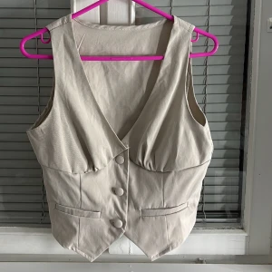 Kostym väst  - Snygg beige väst från Shein med knappar framtill och två fickor. Västen har en v-ringad design och är perfekt för att lägga till en stilren touch till din outfit. Aldrig använt