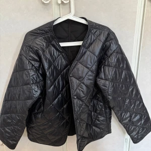 Svart glansig jacka  - Snygg svart glansig jacka med knappar framtill. Jackan har en v-ringad design och långa ärmar,  jackan är en tunn vår jacka som är köpt på Gina tricot och använd 2 gånger, vid funderingar hör av dig!💕