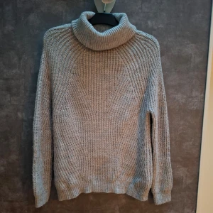 Grå stickad polotröja - Mysig grå stickad polotröja med långa ärmar och ribbade detaljer. Perfekt för kyliga dagar och ger en stilren look. Passar bra till både jeans och kjol. Stor i storlek, passar mig som vanligtvis är M. (XS / 32-34