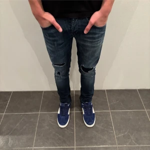 Dondup Jeans - Snygga mörkblå jeans med slitningar på knäna. De har en tight passform och är perfekta för en trendig look. Jeansen har en klassisk femficksdesign och stängs med dragkedja och knapp.