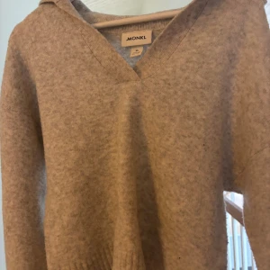 Grå tröja från Monki - Säljer en mysig beige tröja från Monki med v-ringad hals och långa ärmar. Tröjan har en mjuk och bekväm passform.