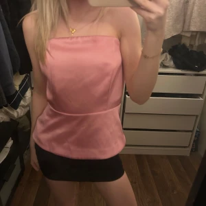Rosa axelbandslös topp - Säljer en stilren rosa axelbandslös topp i ett mjukt material. Toppen har en figurnära passform och är perfekt för en trendig look. Passar bra till både kjol och byxor.