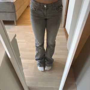 Grå bootcut jeans - Snygga grå bootcut jeans med låg midja från Gina young Snygg design på bakfickorna. Jag är 167 lång och byxorna är lite för långa för mig. Byxorna har inte kommit till användning och är därför anledningen till att jag säljer. Det är storlek 164 men skulle säga att dom är som storlek xs. 