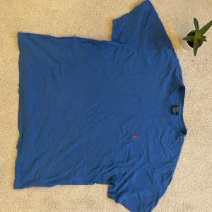 Blå t-shirt från Polo Ralph Lauren - Säljer en klassisk blå t-shirt från Polo Ralph Lauren i storlek XXL. T-shirten är tillverkad i 100% bomull och har en liten röd broderad logotyp på bröstet. Perfekt för en avslappnad stil.