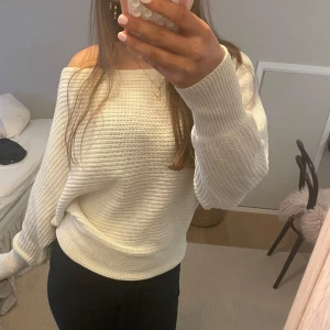 Vit stickad offshoulder tröja - Säljer en stilren vit stickad tröja med offshoulder-design. Tröjan har långa ärmar och en avslappnad passform, perfekt för en trendig look. Passar bra till både jeans och kjol. Perfekt för kyligare dagar!